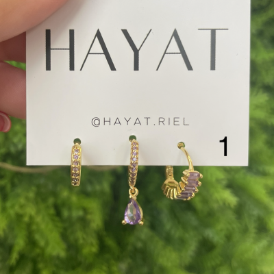 Conjunto de brincos dourados com pedras lilases em cartão da marca HAYAT