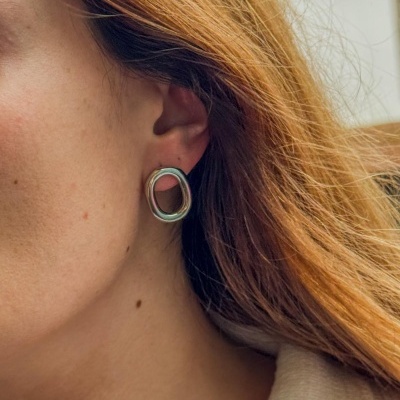 Brinco metálico prateado assimétrico oval no ouvido de mulher