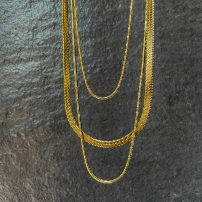 Três correntes douradas penduradas em parede escura texturizada