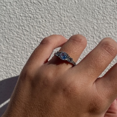 Anel prateado com três pedras brilhantes no dedo de uma mão