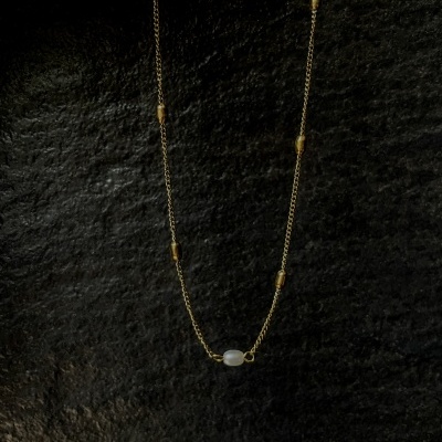 Colar dourado com pedra branca sobre fundo preto