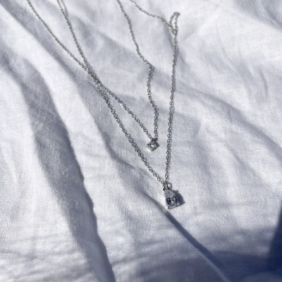 Colar prata com dois pendentes de pedra sobre tecido branco