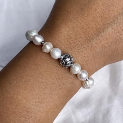 Pulseira de pérolas naturais e metal prateado no pulso de pele morena