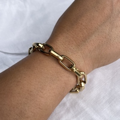 Pulseira de elos metálicos dourados brilhantes no pulso