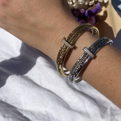 Pulseiras dourada e prateada com pedras brilhantes num pulso