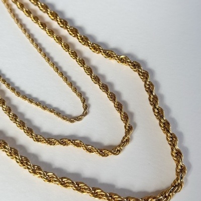 Três correntes douradas torcidas de várias espessuras sobre fundo branco