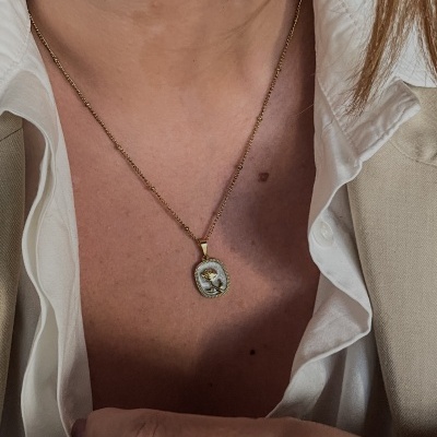 Colar dourado com pendente oval de rosa usada no pescoço
