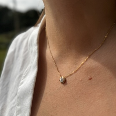 Colar dourado com pendente brilhante usado no pescoço