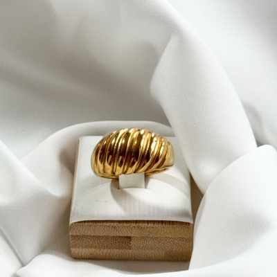 Anel de ouro ondulado em suporte branco sobre tecido branco