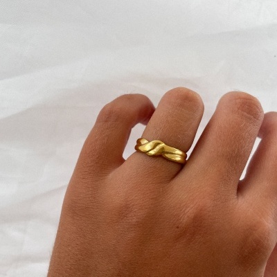 Anel dourado trançado no dedo da mão sobre fundo branco