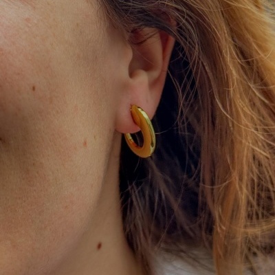 Brinco de argola dourado na orelha de uma pessoa