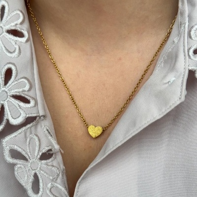 Colar dourado com coração em pendente e camisa branca com bordados de flores