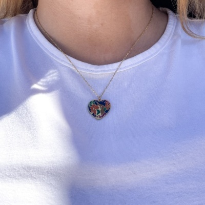Colar com pendente em forma de coração colorido usado com t-shirt branca.
