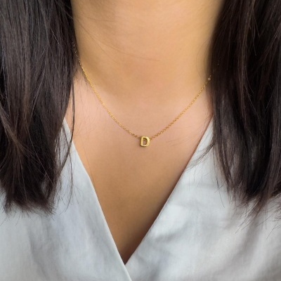 Colar dourado com letra D e blusa branca