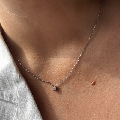 Colar prateado fino com pendente quadrado transparente no pescoço