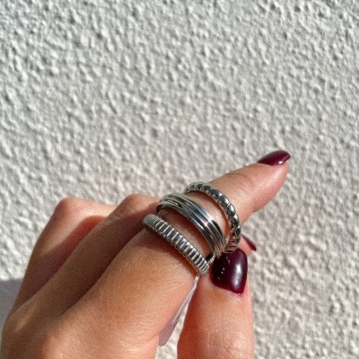 Mão com três anéis prateados e unhas vinho escuro