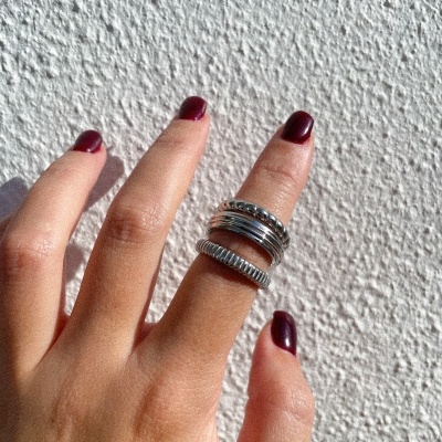 Mão feminina com dois anéis prateados e unhas vermelhas