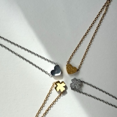 Quatro colares com pendentes variados em dourado e prateado sobre fundo branco