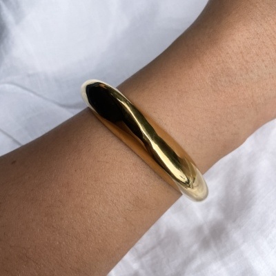 Bracelete dourado brilhante no pulso sobre tecido branco