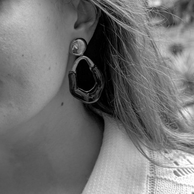 Brinco pendente de forma irregular com base redonda numa orelha feminina