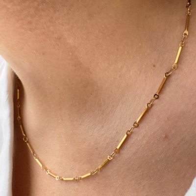 Colar em ouro com elos retangulares finos ao redor do pescoço