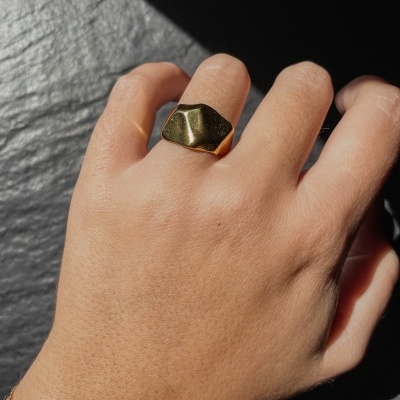 Anel dourado com design irregular usado no dedo da mão esquerda