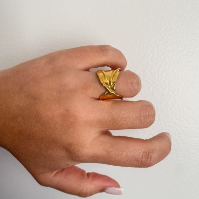 Anel dourado largo em dedo médio de mão com pele castanha