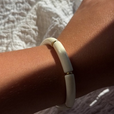 Pulseira branca segmentada com detalhes dourados no pulso