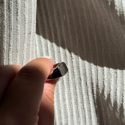 Pendrive metálico prateado segurado por uma mão sobre tecido branco pregueado