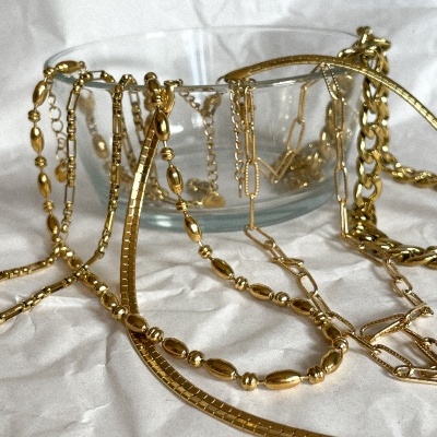 Colares dourados variados sobre superfície branca e em taça de vidro