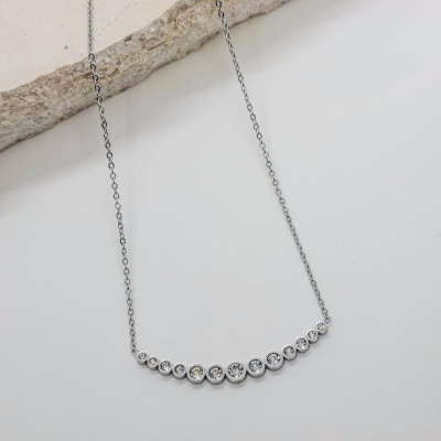 Colar prata com pedras alinhadas sobre fundo branco e pedra clara