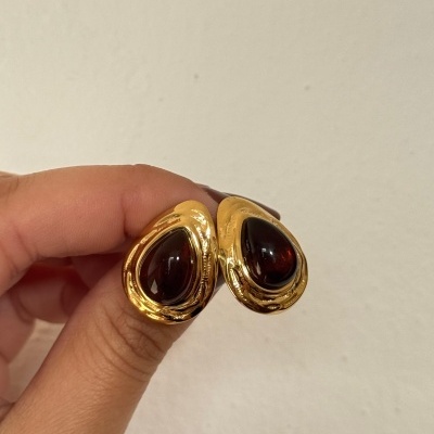 Brincos dourados com gema castanha escura em forma de gota.