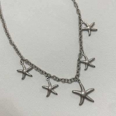 Colar prateado com pendentes estrelas-do-mar em fundo branco