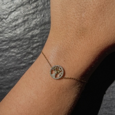 Pulseira dourada com pendente de árvore da vida com cristais no pulso