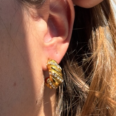 Brinco argola dourado com pedras brilhantes na orelha