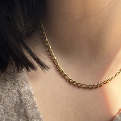 Colar em corrente dourada com elos ovais usados num pescoço feminino