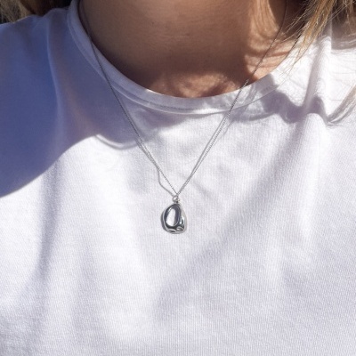 Colar prateado com pendente usado com t-shirt branca