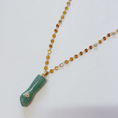 Colar dourado com pendente verde em forma de pé esculpido com pedra brilhante