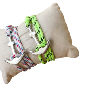 Braceletes com âncoras de metal prateado e cordões coloridos sobre almofada bege