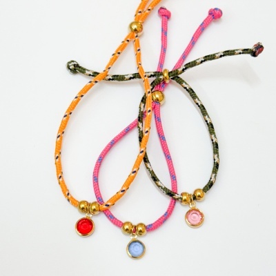 Pulseiras coloridas com contas douradas e pingentes redondos em fundo branco.