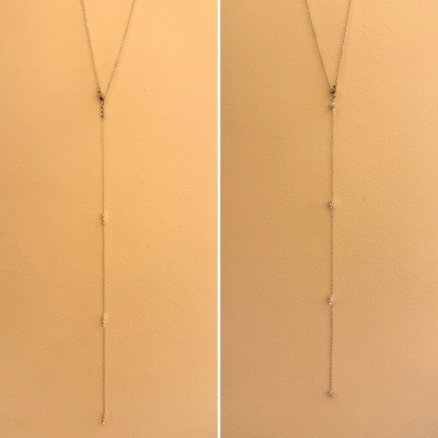 Colar dourado fino com pendentes brilhantes em fundo cor de pêssego