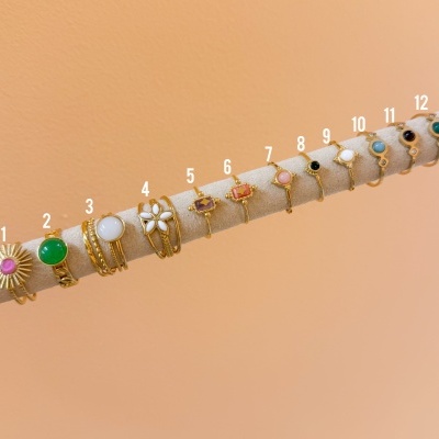 Anéis dorados com pedras coloridas numerados de 1 a 12 em suporte de veludo