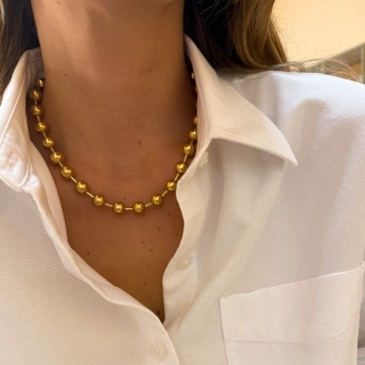 Colar de contas douradas usado com camisa branca