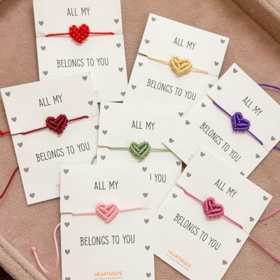 Pulseiras coloridas com coração trançado em cartões brancos com texto
