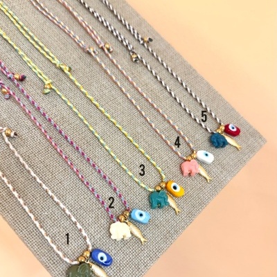 Pulseiras trançadas com pingentes coloridos sobre tecido bege