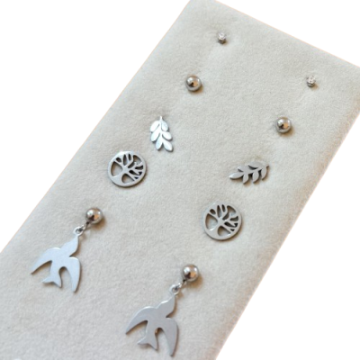 Conjunto de brincos prateados com diferentes formas em fundo bege