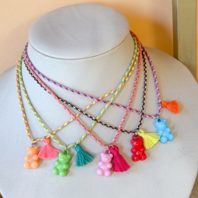 Colares coloridos com ursinhos e franjas em manequim branco