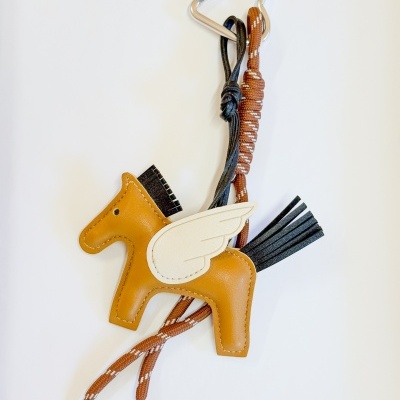 Chaveiro de cavalo em couro castanho com asa branca, pendurado em cordão castanho com mosquetão prateado