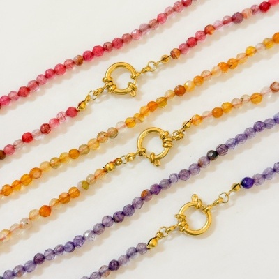 Três pulseiras coloridas de contas facetadas com fechos dourados sobre fundo branco