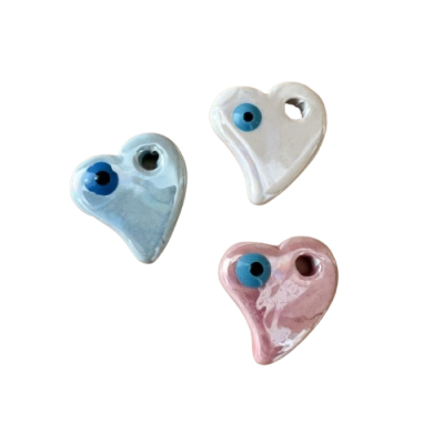 Três corações em cerâmica nas cores azul, branco e rosa, com desenho de olho azul e furo próximo à borda.